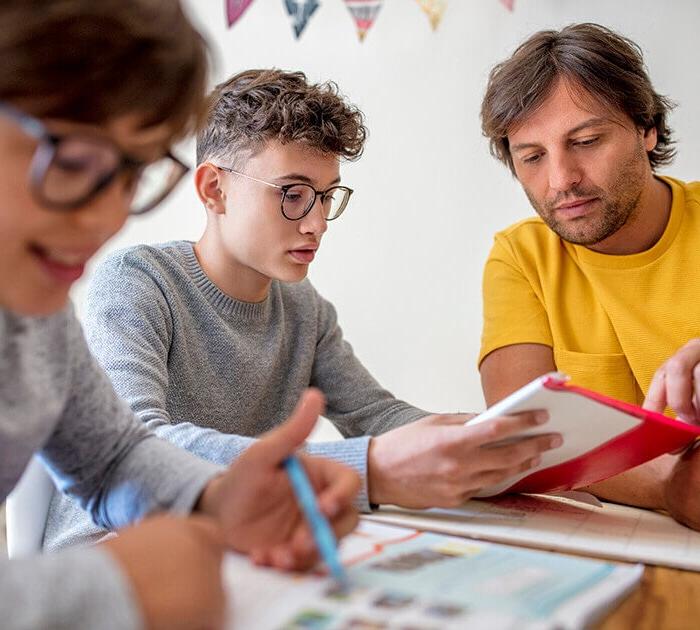 Father and sons studying together at a table - Connections Academy